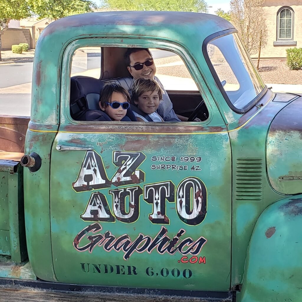 Green vintage work truck with the AZ Auto Graphics door logo, with the owner and his two sons in the cab